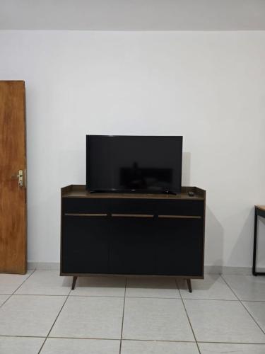 a flat screen tv sitting on top of a dresser at Estúdio Charmoso no Centro de Apiaí in Apiaí