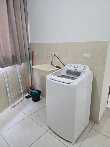 a washing machine in a bathroom with a tile floor at Estúdio Charmoso no Centro de Apiaí in Apiaí