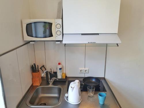 a small kitchen with a sink and a microwave at Aparthotel B & L in Bremen