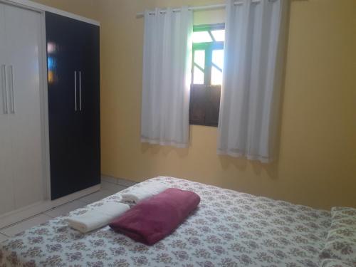 a bed with a purple pillow and a window at Casa do Ed in Lençóis