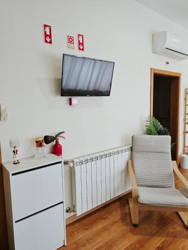 a living room with a chair and a tv on a wall at Junção - Apartamentos Completos in Miranda do Douro