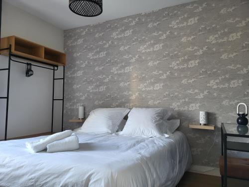 - une chambre avec un grand lit blanc et un mur dans l'établissement T2, centre ville, au calme, à Vannes