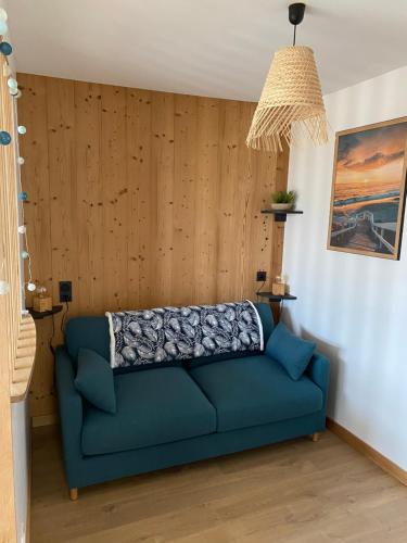 - un canapé bleu dans un salon avec des murs en bois dans l'établissement Au studio cosy, à Chorey-lès-Beaune