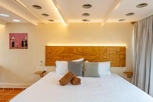 a bedroom with a large white bed with a wooden headboard at Casa Jicama in Cancún