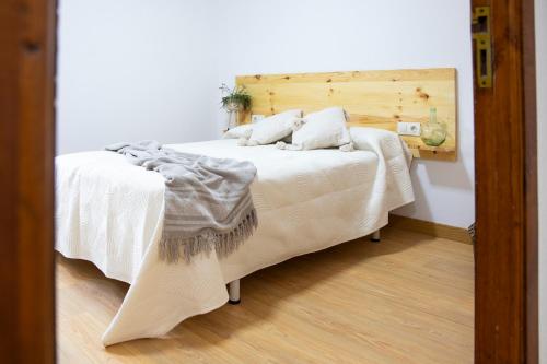 Un dormitorio con una cama blanca con cabecero de madera. en Villa Laudina, en Vilaboa