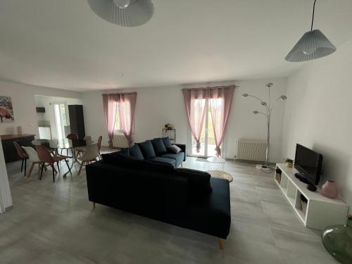 un salon avec un canapé noir et une télévision dans l'établissement Charmante maison de famille, à Ingré