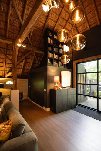 a living room with a couch and a tv at Luxe Hofstede met paardenstalling in Lunteren
