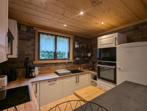 une cuisine avec des appareils blancs et un plafond en bois dans l'établissement Chalet des Belles Roches, 14 pers, garden, sauna, à La Bresse
