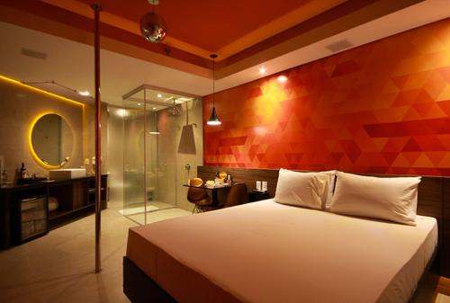 a bedroom with a large bed and a bathroom at Oasis Motel in Piracicaba