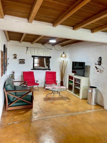 a living room with two red chairs and a table at Hermosa casa finca en Marinilla in Marinilla