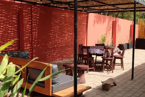 a patio with chairs and tables and a red wall at Exceptional house with sea view in Cap Skirring in Boukot Ouolof