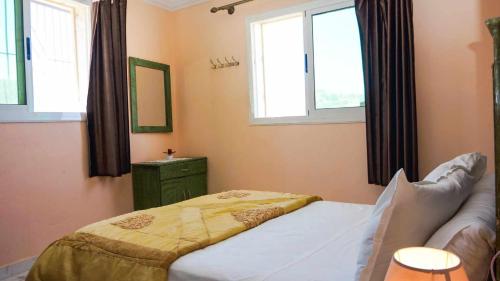 a bedroom with a bed and a couch and two windows at Hotel Ain Leuh in Aïn Leuh