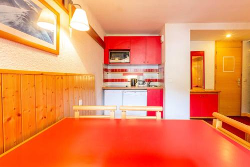 une cuisine avec une grande table en bois et des placards rouges dans l'établissement Résidence Digitale - Résidence DIGITALE N°722 MAE-1631, à La Plagne Tarentaise