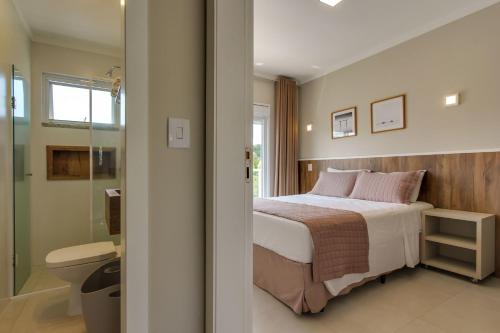 a bedroom with a bed and a bathroom with a toilet at Residencial Casa Flora in Bombinhas