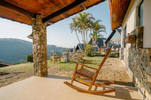 a wooden rocking chair sitting on the porch of a house at Pousada das Pedras in Monte Verde