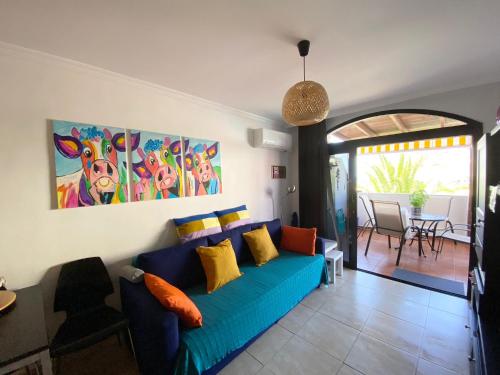 Una sala de estar con un sofá azul con almohadas de colores. en Sweet Home on the Beach 212, en Mogán