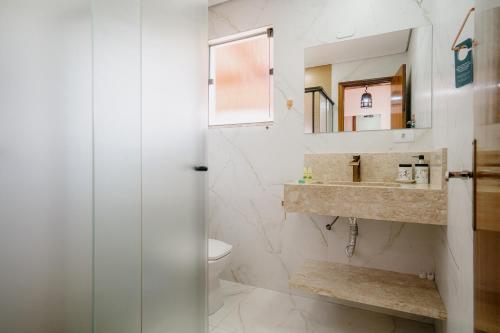 a bathroom with a toilet and a sink and a mirror at Pousada das Pedras in Monte Verde