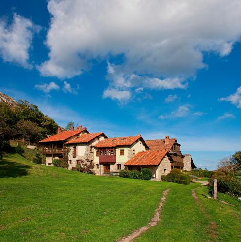 a house with red roofs on a green field at La Montaña Mágica Hotel Rural in Vibaño