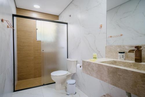 a bathroom with a toilet and a shower and a sink at Pousada das Pedras in Monte Verde
