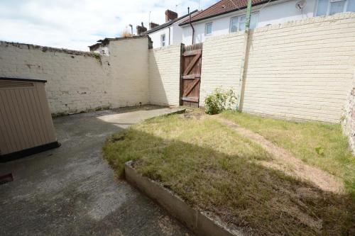 a backyard with a brick wall and a garage at Stylish Retreat near Birkenhead & Liverpool Your Cozy Home Away From Home in Wallasey