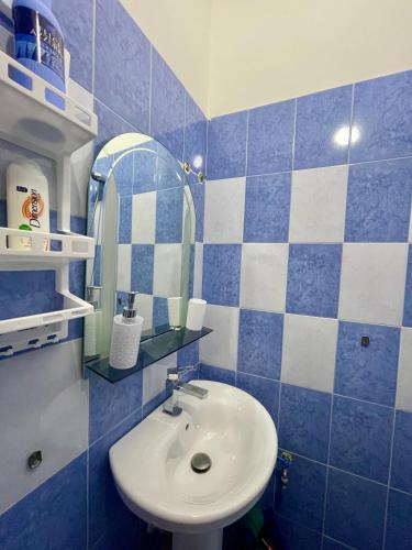 un bagno piastrellato di blu con lavandino e specchio di Barbaras room a Shkodër