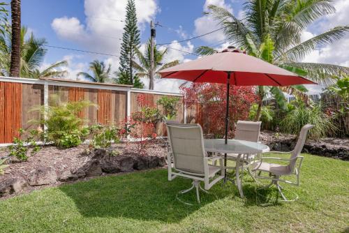 a table and chairs with an umbrella on the grass at Pahoa Paradise Palms in Pahoa
