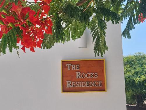 a sign on a white wall with red flowers at The Rocks Residence, apartment 2 of total 2 in Paradera