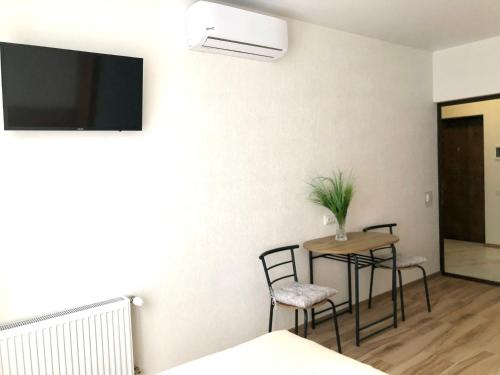 a room with a table and chairs and a tv on the wall at OSapart hotel in a complex Semycvit 8 in Lviv
