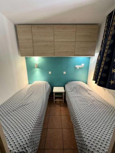 une chambre avec deux lits et un mur bleu dans l'établissement Résidence Rivages - Appartement T2 dans le domaine de la Coudoulière a deux pas de la mer MAE-0721, à Six-Fours-les-Plages