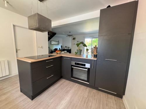 - une cuisine avec des armoires noires et une cuisinière dans l'établissement La Petite Citadine Proche Futuroscope, à Poitiers