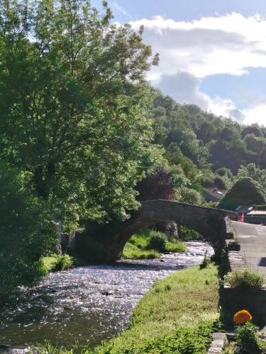 an old stone bridge over a river at Chambre privée au pays des volcans in Massiac