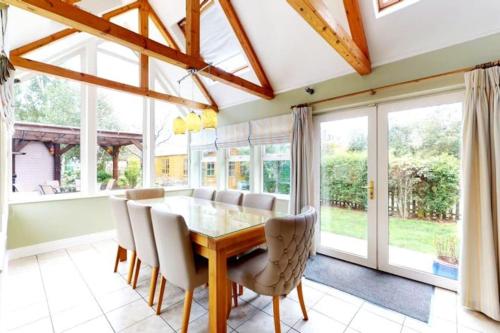 a dining room with a table and chairs and windows at Donabate 5BD Home 10 min to Airport in Donabate