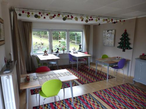 ein Zimmer mit Tischen und Stühlen und einem Weihnachtsbaum in der Unterkunft Gästehaus HarzGlück in Braunlage