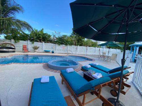 a pool with blue lounge chairs and an umbrella at Ocean View with Pool, 4 bedroom Vila Near Key West in Cudjoe Key