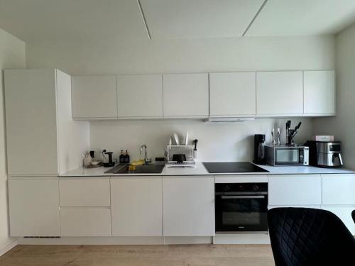 a white kitchen with white cabinets and a microwave at Flot Moderne Lejlighed byder Velkommen in Vesterled