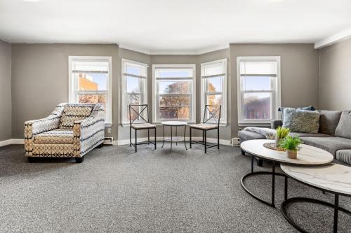 a living room with a couch and chairs and windows at Downtown Beverly Apartment 8 Minutes to Salem and has King Beds in Beverly