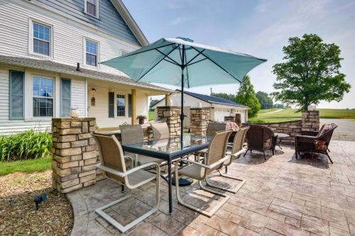 a patio with a table with chairs and an umbrella at Countryside Home in Wooster with Patio and Fire Pit in Wooster