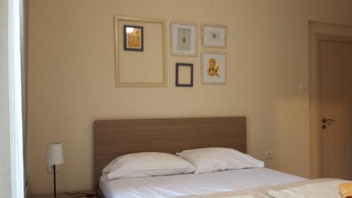 a bedroom with a bed with white pillows and pictures on the wall at Apartments Fortunella in Budva
