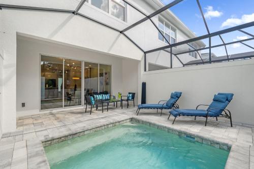 a swimming pool with blue chairs and a house at Upstay - Townhouse with Private Pool and Foosball in Orlando
