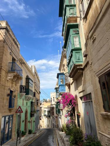 an alley with colorful buildings and flowers on a street at Authentic Maltese Boutique Holiday Home with Rooftop Pool - Moon Townhouse in Cospicua