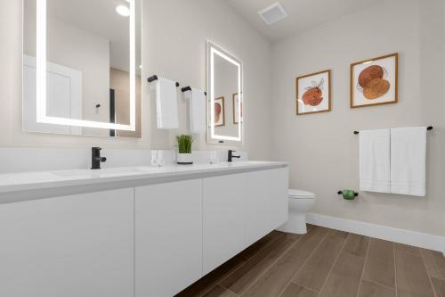 a white bathroom with two sinks and a toilet at Upstay - Townhouse with Private Pool and Foosball in Orlando