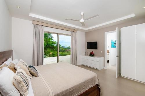 a white bedroom with a bed and a television at Exclusive Villa in Mar Vista Community in Playa Flamingo