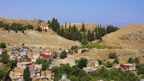 a small village on a hill with trees and buildings at Hotel Ain Leuh in Aïn Leuh
