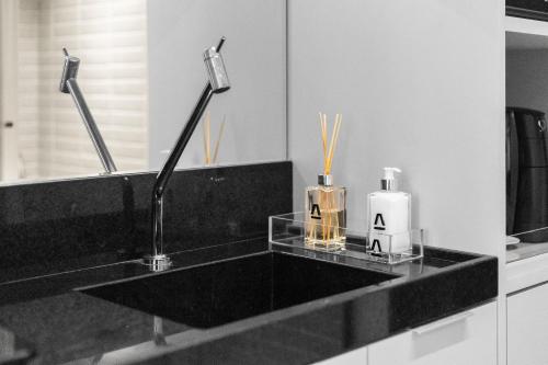 a bathroom counter with a black sink and a bottle of soap at Alta Garden Housi João Pessoa by Carpediem in João Pessoa