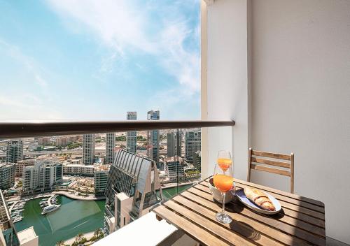 迪拜Luxury Beachfront 2Bd Apt, Shams, JBR的阳台上摆着一张木桌，桌上放着一杯葡萄酒。
