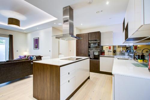 a large kitchen with white cabinets and a kitchen island at Newlands Pepe by Artsy in London