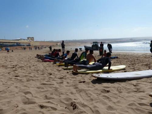a group of people sitting on surfboards on a beach at Oasis TIFNIT Villa with Pool View No vis A vis in Draïd