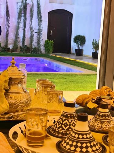a table with glasses and plates on it with a pool at Oasis TIFNIT Villa with Pool View No vis A vis in Draïd