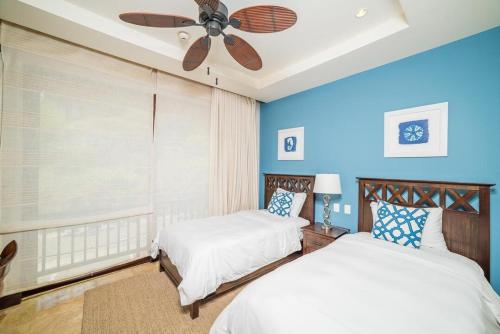 two beds in a bedroom with blue walls and a ceiling fan at Captivating Ocean Views Condo with Pool in Ocotal
