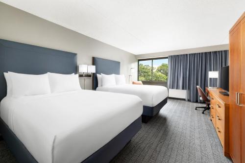 a hotel room with two beds and a desk at Courtyard Montvale in Montvale
